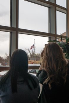 people looking out the window at a flag