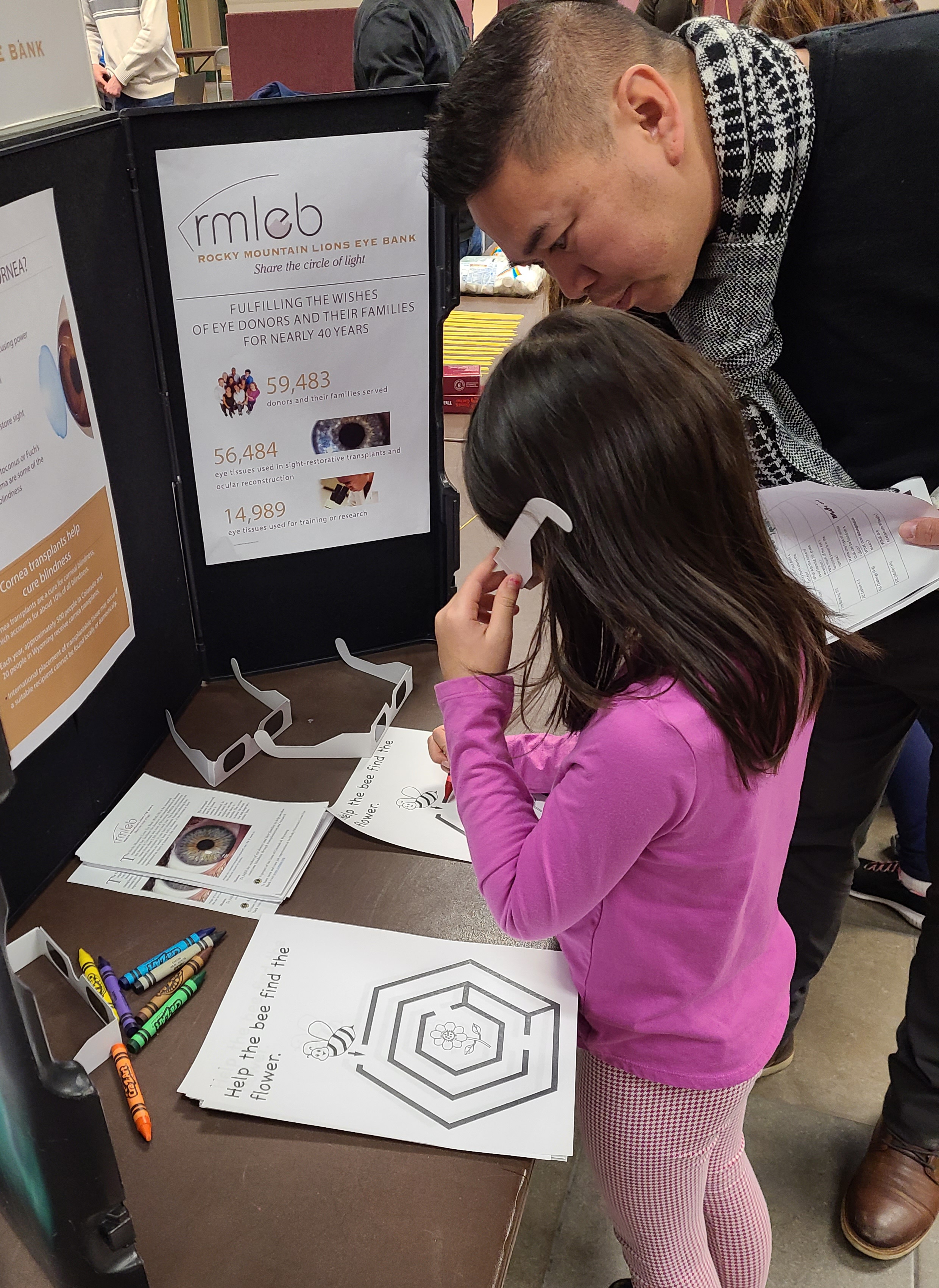 Photo of father and daughter trying on glasses that simulate blindness.