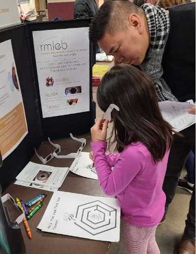 Photo of father and daughter trying on glasses that simulate blindness.